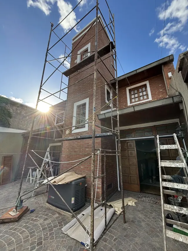 Frente de casa de ladrillo con andamio para trabajos en altura