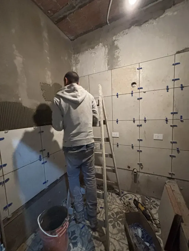 Albañil colocando porcelanato en la pared de un baño